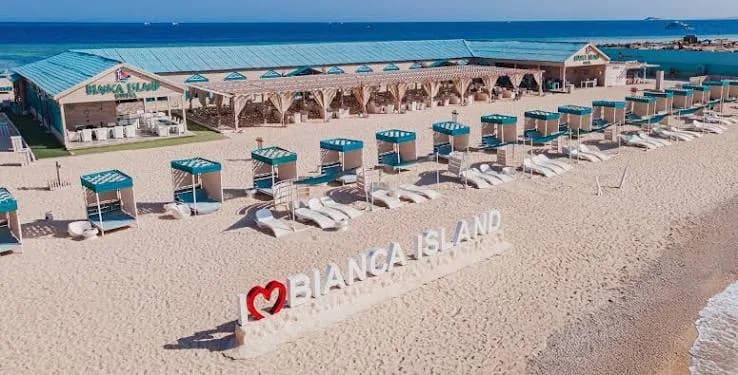Bianca Island beach sign with rows of cabana daybeds along the shoreline