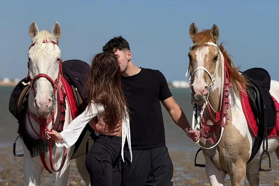 Guests walking with horses by the coast