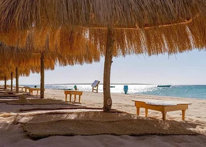 Straw-roofed sunshade loungers along the beach at Paradise Island