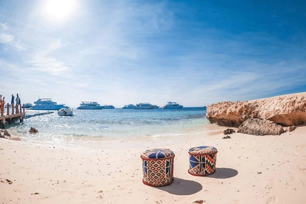 Bedouin-style poufs on the beach with anchored cruise boats at Paradise Island