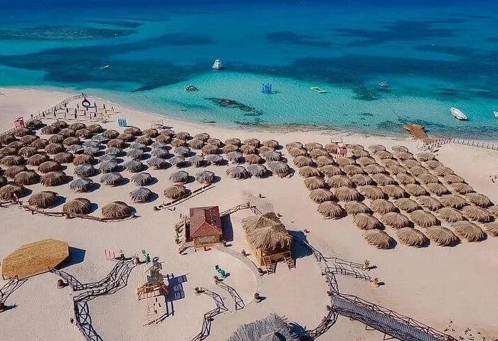 Aerial view of straw-umbrella sun loungers and beach club facilities at Paradise Island