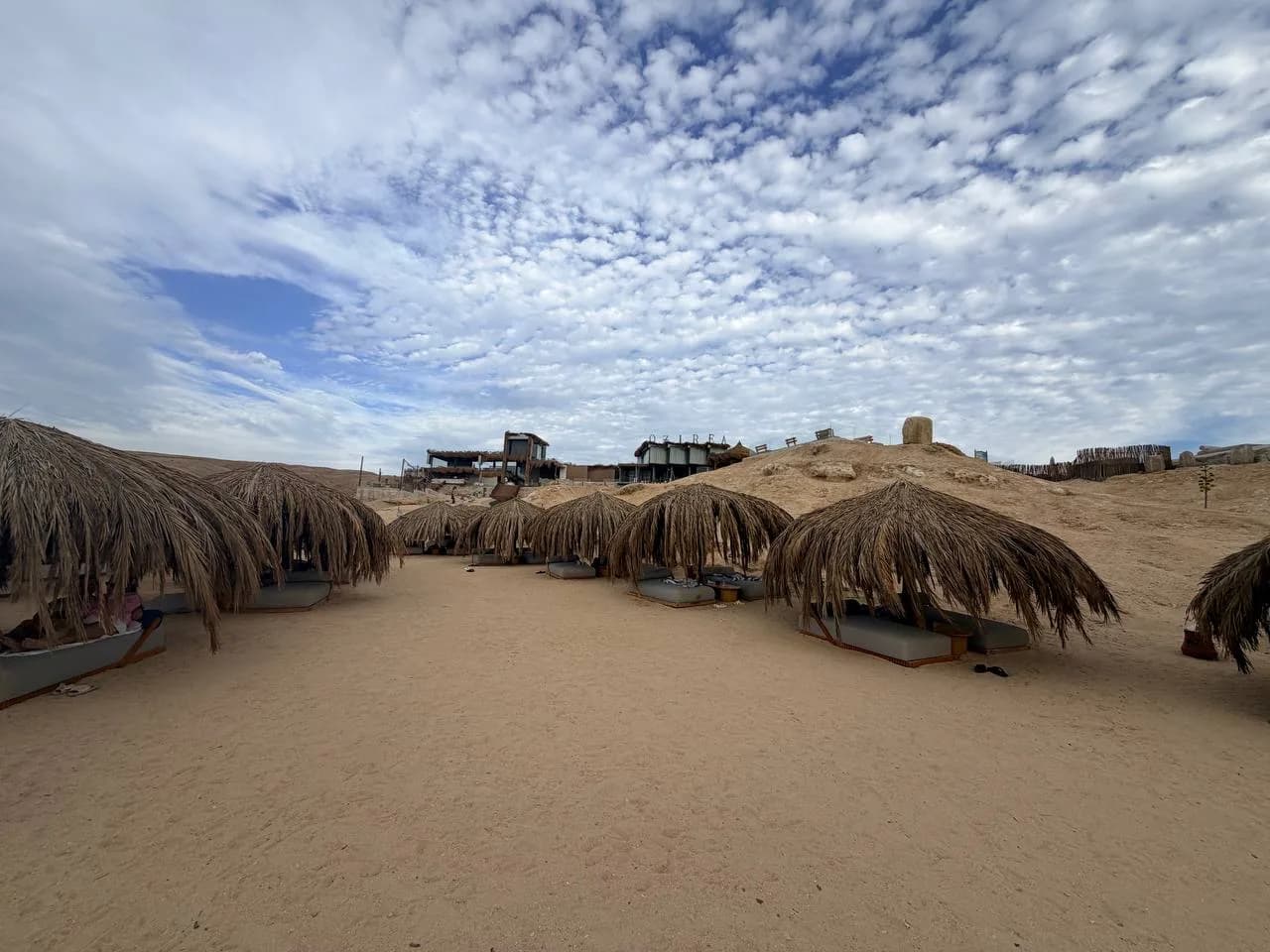 OZIREA sign with thatched beach loungers on the sand
