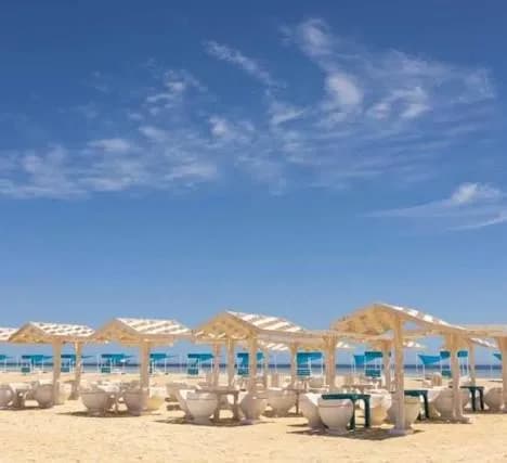 Rows of white sun loungers under wooden shade canopies on the beach at Bianca Island
