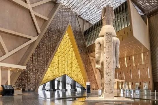Ancient Egyptian statue inside the golden triangular atrium of the Grand Egyptian Museum