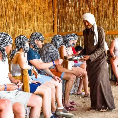 Guests seated at the Bedouin village being served traditional Egyptian tea