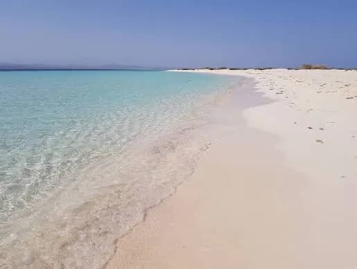 Clear turquoise water meeting a white sand beach on a Hamata island