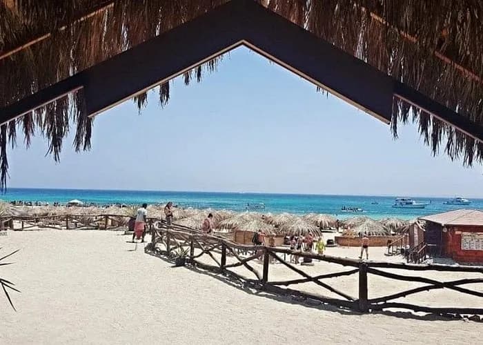 View of the beach and turquoise lagoon from under a thatched shelter at Ozirea Island
