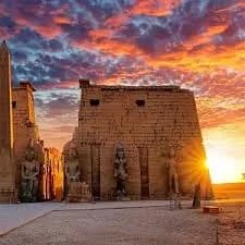 Luxor Temple's entrance pylon silhouetted against a dramatic sunset sky