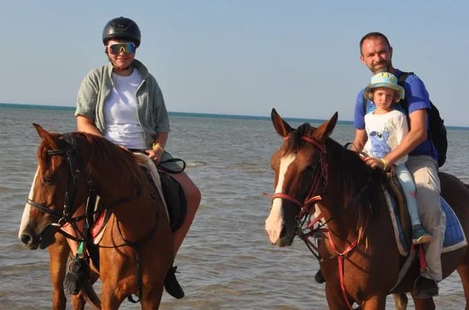 Family horse riding in shallow sea water