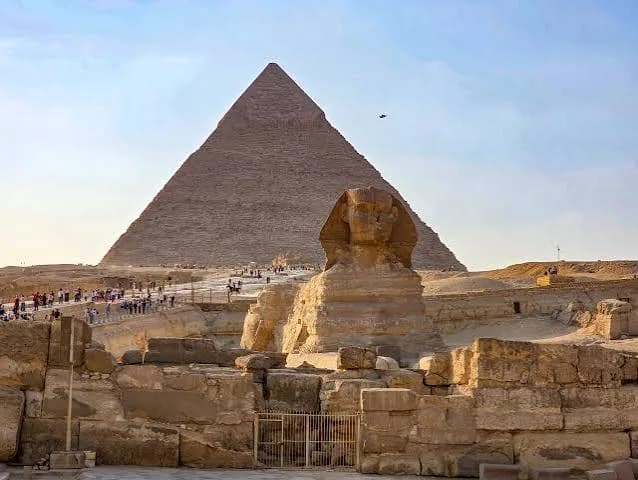 The Great Sphinx of Giza with the Pyramid of Khafre behind it and visitors nearby