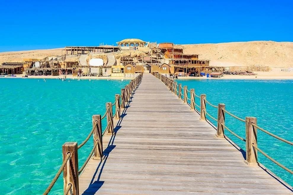 Wooden footbridge leading to the island beach club over turquoise lagoon water