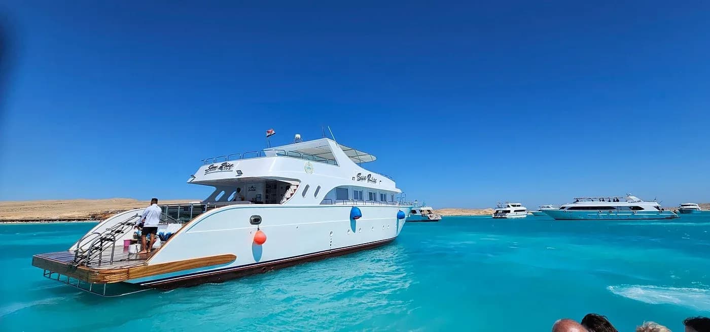 A Harmony Tours Red Sea boat anchored in turquoise water with other excursion boats nearby