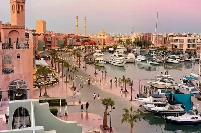 Hurghada's marina promenade at dusk, with fishing boats and the city's mosque minarets in the background