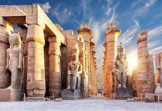 Luxor Temple's colonnade at sunset, with the colossal seated statues of Ramesses II